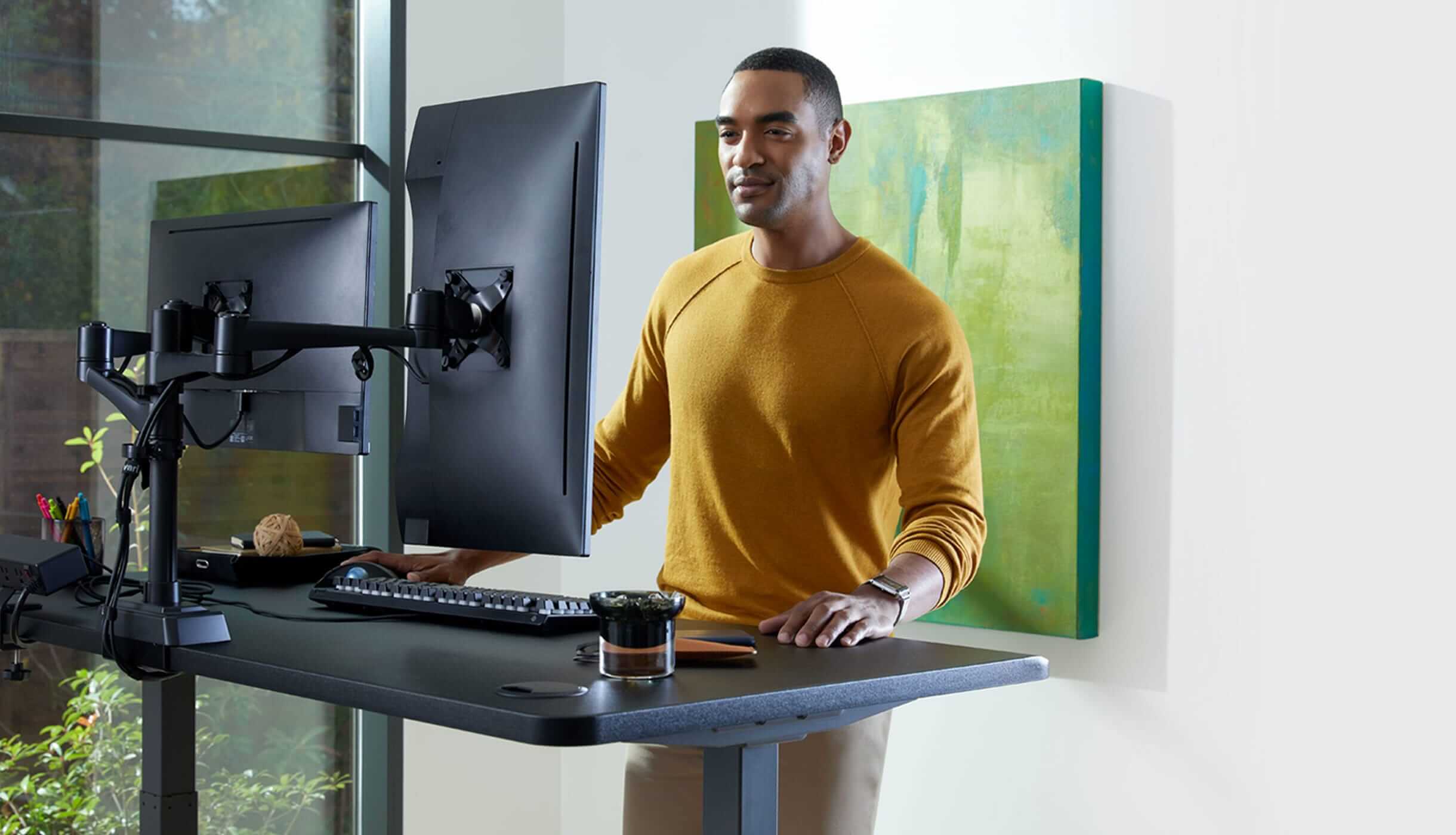 individual working at an electric standing desk and dual monitor arms